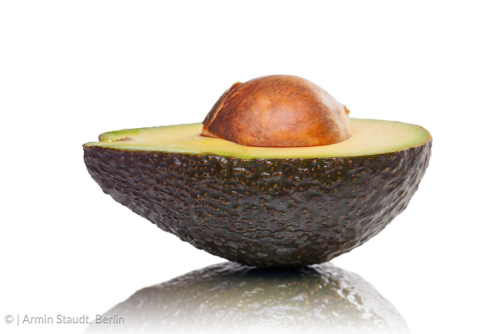 half of an avocado with kernel and reflection, isolated on white