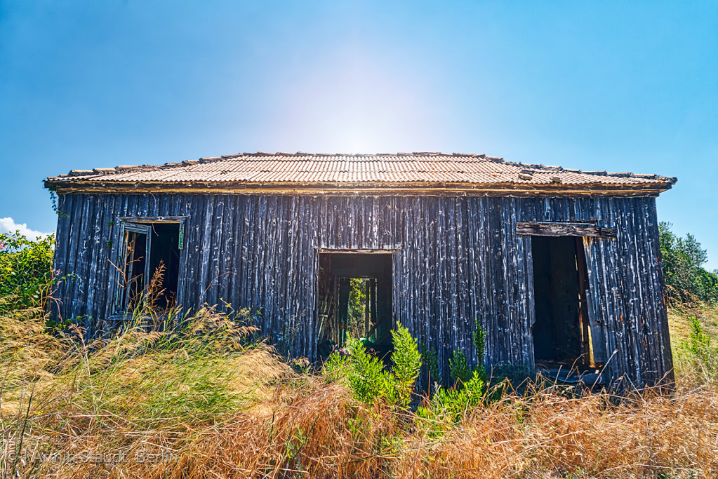 old abandoned wooden cottage with the sun behind