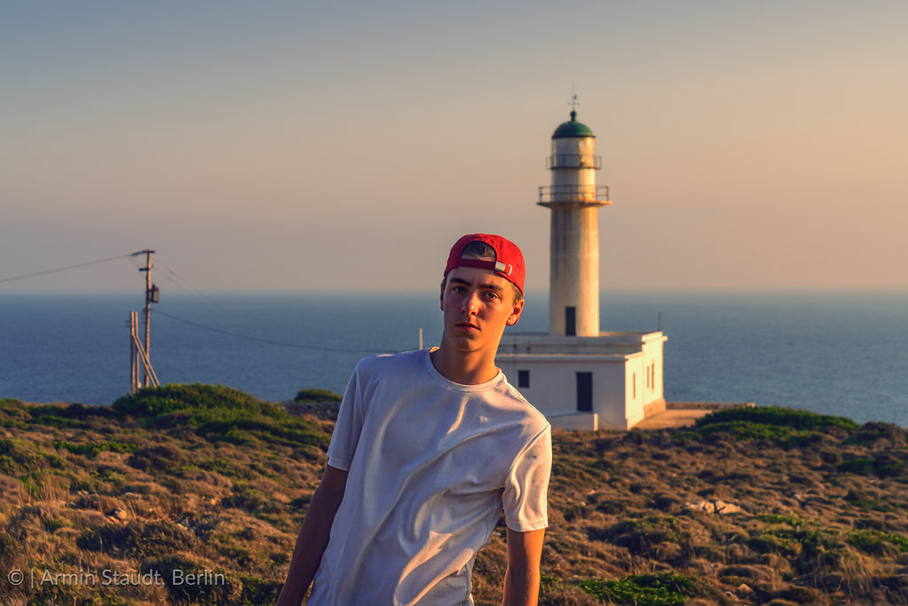portrait of a young man in front of a lighthouse in Greece